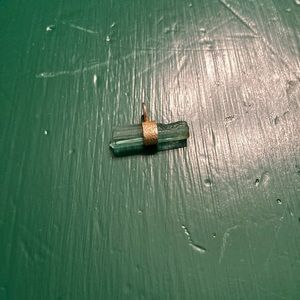Unique raw aqua tourmaline set in gold coloured metal small bar pendant.